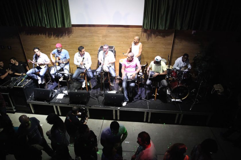 Apresentação musical de colaboradores da Toledo do Brasil em evento interno com banda no palco e público reunido em frente, promovendo integração entre funcionários por meio da música.